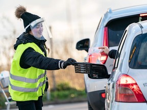 A COVID-19 test is handed out of a car at a car park at Svagertorp railway station in Malmo, Sweden, on Nov. 26, 2020.
