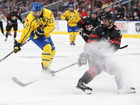 Canada's Justin Barron (2) spins in an attempt to stop Sweden's Alexander Holtz (27) from shooting in the Hlinka Gretzky Cup in Edmonton on Aug. 8, 2018.