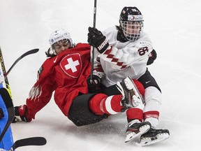 Switzerland's Noah Delemont (4) is checked by Austria's Finn van Ee (26) during the second period of an IIHF World Junior Hockey  Championship pre-competition game in Edmonton on Dec. 22, 2020.