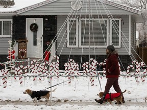 An area resident walks their dogs past Christmas displays along 148 Street between 100 Avenue to 92 Avenue, in Edmonton Friday Dec. 11, 2020.