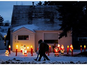 Pedestrians make their way past a series of vintage Christmas decorations in a font yard near 92 Street 90 Avenue in Edmonton on Wednesday, Dec. 23, 2020.