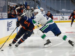 Connor McDavid (97) of the Edmonton Oilers battles against Alexander Edler (23) of the Vancouver Canucks at Rogers Place on Wednesday, Jan. 13, 2021.
