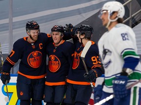 Connor McDavid, left, Tyson Barrie, centre, and Ryan Nugent-Hopkins, right, of the Edmonton Oilers celebrate a goal against the Vancouver Canucks at Rogers Place on January 14, 2021.