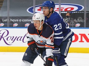 Dominik Kahun (No. 21) of the Edmonton Oilers battles against Travis Dermott (No. 23) of the Toronto Maple Leafs during an NHL game at Scotiabank Arena on Jan. 20, 2021.