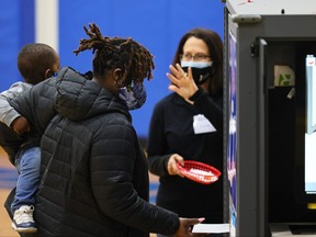 A woman holding a young child casts her vote in the Georgia run-off election at Dunbar Neighborhood Center on Jan. 5, 2021 in Atlanta, Ga.