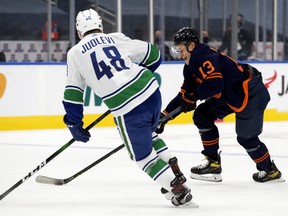 The Edmonton Oilers forward Jesse Puljujarvi (No. 13) battles the Vancouver Canucks defenceman Olli Juolevi (No. 48) during first period NHL action, in Edmonton Thursday Jan. 14, 2021.