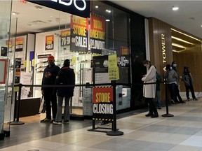 Shoppers line up at a store in Edmonton City Centre Mall on Friday, Dec. 11, 2020 in Edmonton. With new COVID-19 restrictions going into effect Sunday in Alberta some shoppers are taking advantage of the last days of looser retail rules .
