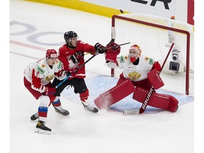 Canada's Dylan Holloway (10) reaches for the puck as does Russia's Yaroslav Askarov (1) and Yan Kuznetsov (2) during first period IIHF World Junior Hockey Championship semifinal action on Monday, Jan. 4, 2021 in Edmonton.