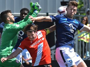 After FC Edmonton Amer Didic, right, and Cavalry FC Mason Trafford (5) went up for the header, goalkeeper Marco Carducci (1) punched the ball away during Canadian Premier League action at Clarke Stadium in Edmonton, June 15, 2019.