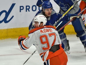 Edmonton Oilers captain Connor McDavid (97) and Toronto Maple Leafs forward Auston Matthews (34) wheel after the puck at Rogers Place in Edmonton on Saturday, Jan. 30, 2021.