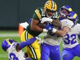 Green Bay Packers running back AJ Dillon (28) runs with the ball while Los Angeles Rams safety Nick Scott (33) and linebacker Troy Reeder (51) attempt to tackle him Saturday at Lambeau Field.