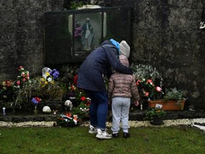 Denise Gormley and her daughter Rosa, 7, pay their respects at the Tuam graveyard, where the bodies of 796 babies were uncovered at the site of a former Catholic home for unmarried mothers and their children, on the day a government-ordered inquiry into former Church-run homes for unmarried mothers is formally published, in Tuam, Ireland, Tuesday, Jan. 12, 2021.