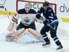 Winnipeg Jets forward Andrew Copp (right) attempts to tip a shot past Edmonton Oilers goaltender Mikko Koskinen in Winnipeg on Tues., Jan. 26, 2021.