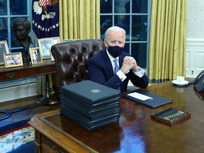U.S. President Joe Biden signs executive orders inside the Oval Office at the White House in Washington, U.S., January 20, 2021.
