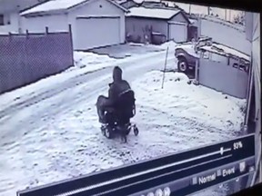 Surveillance footage outside a disabled Edmonton senior's home shows a thief riding her $4,000-power wheelchair down her driveway. Screenshot.