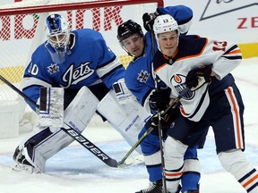 Winnipeg Jets defenceman Neal Pionk (centre) has his hands full with Edmonton Oilers forward Jesse Puljujarvi in front of goaltender Laurent Brossoit in Winnipeg on Sun., Jan. 24, 2021.