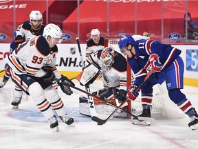 Goaltender Mike Smith #41 of the Edmonton Oilers protects his net while teammate Ryan Nugent-Hopkins #93 defends against Brendan Gallagher #11 of the Montreal Canadiens during the second period at the Bell Centre on February 11, 2021 in Montreal, Canada.