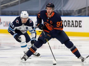 Connor McDavid (97) of the Edmonton Oilers skates the puck against Mark Scheifele (55) of the Winnipeg Jets at Rogers Place on Feb. 17, 2021.