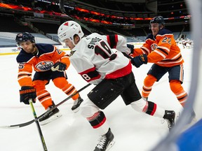 Edmonton Oilers Tyson Barrie (22) and Darnell Nurse (25) battle Ottawa Senators forward Tim Stutzle (18) at Rogers Place in Edmonton on Feb. 2, 2021.