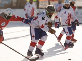 Scott Bentley wears a wintry hat over his bucket as players play in the home stretch of the World’s Longest Hockey Game at Saikers Acres in Sherwood Park, outside of Edmonton, on Sunday, Feb. 14, 2021.