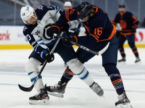 Edmonton Oilers’ Jujhar Khaira (16) battles Winnipeg Jets’ Trevor Lewis (23) during first period NHL action at Rogers Place in Edmonton, on Monday, Feb. 15, 2021.