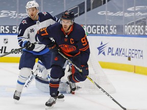 Winnipeg Jets defensemen Neal Pionk (4) battles for position with Edmonton Oilers forward Connor McDavid (97) during the first period at Rogers Place.