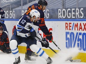 Winnipeg Jets forward Jansen Harkins (12) and Edmonton Oilers defensemen Evan Bouchard (75) battle for loose puck during the second period at Rogers Place on Feb. 15, 2021.