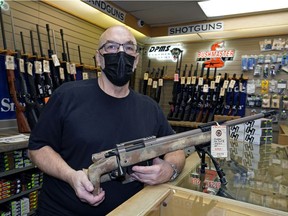 Phil Harnois, co-owner of P & D Enterprises gun shop, hold a firearm on Tuesday, Feb. 16, 2021.