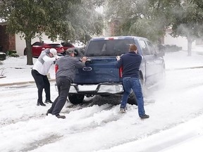 Residents help a pickup truck driver get out of ice on the road in Round Rock, Texas, on Wednesday, Feb. 17, 2021.