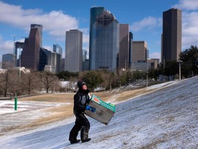 A boy walks up a snow covered hill after sledding down it in a box in Houston, Texas on Feb. 15, 2021.
