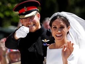 Britain's Prince Harry gestures next to his wife Meghan as they ride a horse-drawn carriage after their wedding ceremony at St George's Chapel in Windsor Castle in Windsor, Britain, May 19, 2018.