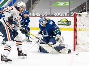 Goalie Thatcher Demko of the Vancouver Canucks makes a save against Connor McDavid (No. 97) of the Edmonton Oilers during the first period of NHL action at Rogers Arena on March 13, 2021 in Vancouver, Canada.