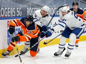 Edmonton Oilers’ Connor McDavid (97) battles Toronto Maple Leafs’ Justin Holl (3) and John Tavares (91) during third period NHL action at Rogers Place in Edmonton, on Monday, March 1, 2021.