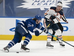 Edmonton Oilers center Connor McDavid (97) moves the puck against Toronto Maple Leafs defenseman Justin Holl (3) during the second period at Scotiabank Arena on March 27, 2021.