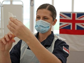 In this file photo taken on Jan. 27, 2021 Royal Navy medics prepare syringes ahead of giving injections of the Oxford/AstraZeneca COVID-19 vaccine to members of the public at a vaccination centre set up at Bath racecourse in Bath, southwest England.