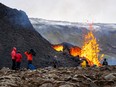 People get up close as lava flows from the erupting Fagradalsfjall volcano some 40 km west of the Icelandic capital Reykjavik, on March 23, 2021.