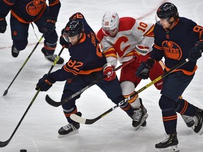 Edmonton Oilers Caleb Jones (82) and Gaetan Haas (91) squeeze Calgary Flames Derek Ryan (10) during NHL action at Rogers Place in Edmonton, March 6, 2021.