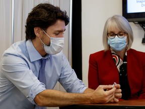 Prime Minister Justin Trudeau, with Minister of Health Patty Hajdu, holds an empty COVID-19 vaccine vial at the Civic Hospital in Ottawa December 15, 2020.