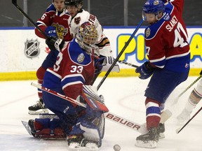 The Edmonton Oil Kings' goaltender Sebastian Cossa (33) and Keagan Slaney (47) battle the Calgary Hitmen during first period WHL action, in Edmonton Friday March 26, 2021. Photo by David Bloom