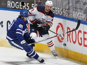 Kris Russell #4 of the Edmonton Oilers clears a puck past John Tavares #91 of the Toronto Maple Leafs during an NHL game at Scotiabank Arena on March 27, 2021 in Toronto.