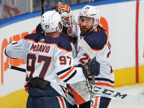 Connor McDavid (97) and Leon Draisaitl (29) of the Edmonton Oilers congratulate teammate Mike Smith (41) after their victory against the Toronto Maple Leafs at Scotiabank Arena on March 29, 2021, in Toronto.