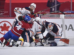 Adam Larsson #6 of the Edmonton Oilers takes down Phillip Danault #24 of the Montreal Canadiens as goaltender Mike Smith #41 covers the puck during the first period at the Bell Centre on April 5, 2021 in Montreal.