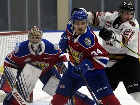 Edmonton Oil Kings centre Kaid Oliver (34) battles the Calgary Hitmen's Riley Fiddler-Schultz (21) in front of goaltender Sebastian Cossa (33) in Edmonton on March 26, 2021.