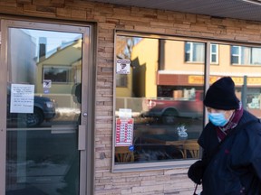 A walker wearing a COVID-19 face mask passes the Golden Bird restaurant, which has been temporarily closed, on 97 Street near 105 Avenue in Edmonton on Dec. 4, 2020.