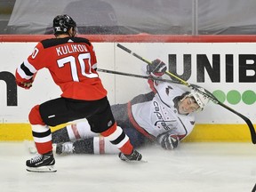 Washington Capitals right wing T.J. Oshie (77) slides into the boards after colliding with New Jersey Devils defenseman Dmitry Kulikov (70) during the second period at Prudential Center on April 4, 2021.