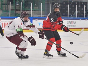 makes a pass in front of Martins Sulcs (No. 24) of Latvia in a group game at the IIHF U-18 world championship in Frisco, Tex., on April 28, 2021.