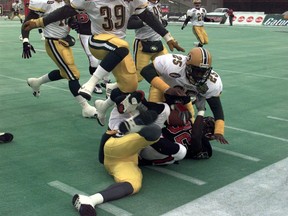 Edmonton Football Team defensive back Don Wilson (25) hits the pile to bring down Calgary Stampeders ball carrier Kelvin Anderson (32) in the West Division final on Nov. 14, 1998.