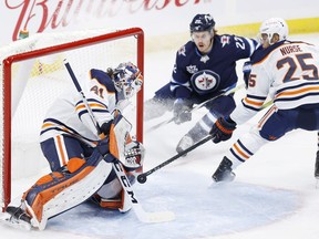 Winnipeg Jets center Mason Appleton (22) and Edmonton Oilers defenseman Darnell Nurse (25) watch as Edmonton Oilers goaltender Mike Smith (41) blocks a shot in the first period at Bell MTS Place on April 17, 2021.