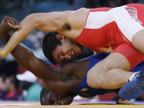 Khetag Pliev of Canada, (in red) and Javier Cortina Lacerra of Cuba, (in blue) compete during their 66-kg freestyle wrestling match at the 2012 Summer Olympics, Sunday, Aug. 12, 2012, in London.