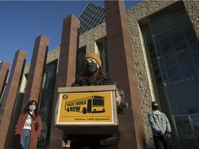 Free Transit Edmonton organizers Danika McConnell, left, Paige Gorsak and Cole Rockarts prepare to deliver a petition with 1,400 signatures demanding city council freeze public transit cash fares at city hall on Monday April 12, 2021.